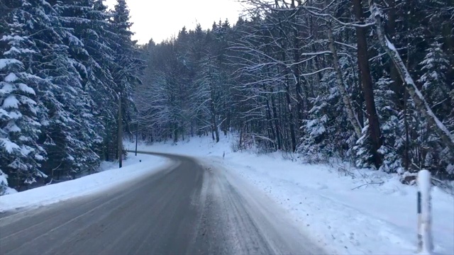 在寒冷的冬天的早晨，在积雪的路上穿过森林视频素材