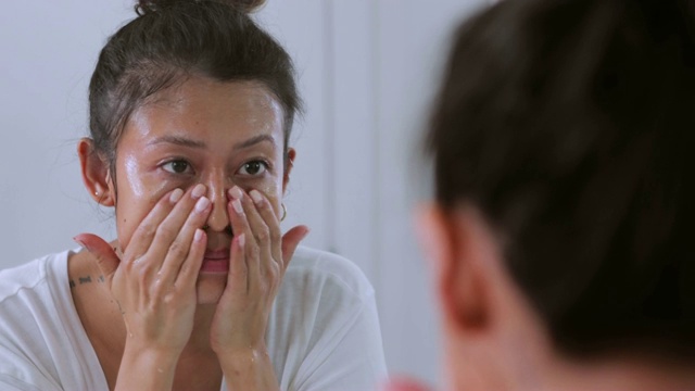 可爱的亚洲女孩在浴室镜子里洗脸视频素材