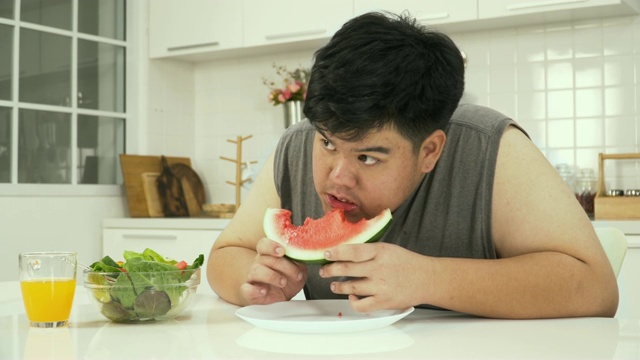 侧面图:泰国超重男子吃西瓜等健康食品时感到饥饿视频素材