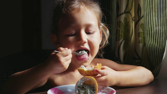 孩子正在吃早饭。可爱小女孩吃百香果的肖像。视频素材