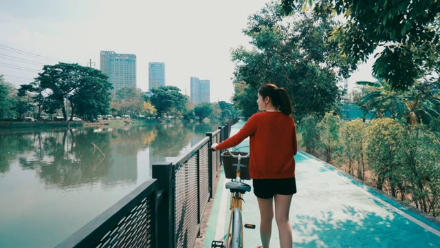 美丽的女孩，她在公园的自行车道上快乐地骑车。视频素材