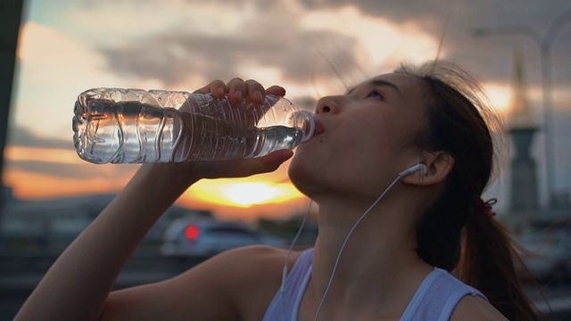 年轻的亚洲女运动员跑步后喝水，慢动作视频素材