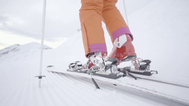 中镜头女滑雪者在滑雪束缚在慢动作滑雪后视图视频素材