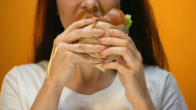 女人咬不可口的汉堡包，不满意的食物质量，特写视频素材