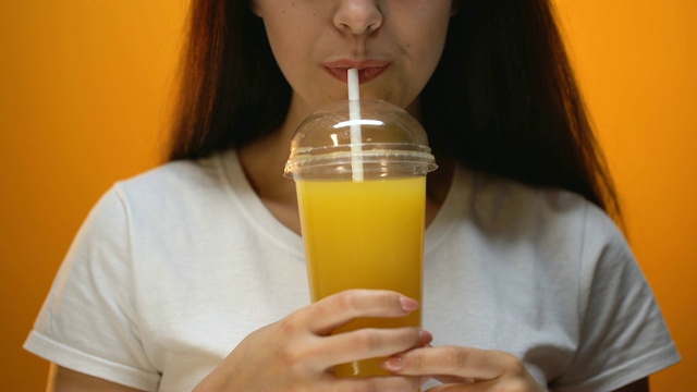 女孩喝橙汁，坚持健康饮食和维生素平衡，特写视频素材