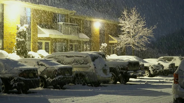 2018年1月13日，美国纽约:冬季汽车大灯下的雪地土路夜景。冬天的暴风雪在黄昏时分在路灯下下了一场大雪视频素材