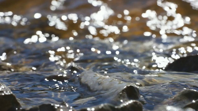 海浪拍打着海滩上的石头。水拍打着海岸上的卵石。小波浪冲击着海岸线上的岩石。视频下载