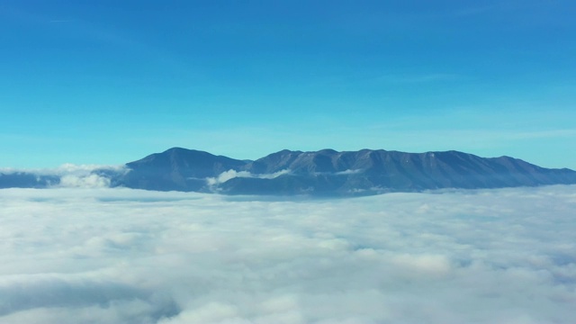 鸟瞰图的云和雾滩在一个美丽和多彩的森林与一些山的背景。视频素材