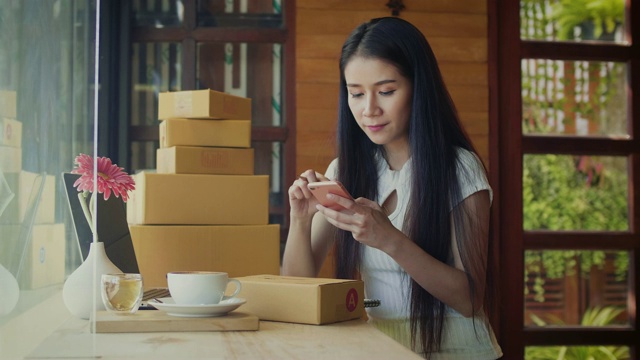 美丽的亚洲女性自由职业者使用她的智能手机和工作在咖啡店视频素材