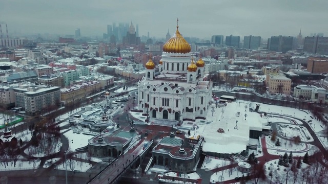 航拍莫斯科冬季俄罗斯东正教救世主神庙。到处都在下雪。大教堂周围有风景名胜、历史建筑、莫斯科城和斯大林式的摩天大楼。视频素材