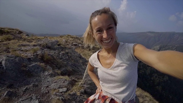 一名兴高采烈的年轻女子一路登山到达山顶后在山顶自拍;人们享受夏日户外活动理念视频素材