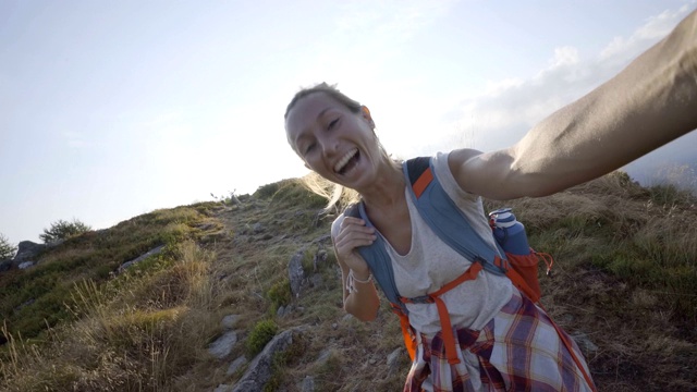 一名兴高采烈的年轻女子一路登山到达山顶后在山顶自拍;人们享受夏日户外活动理念视频素材