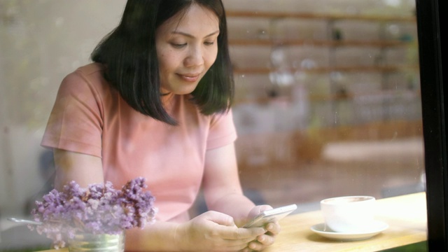 女人用智能手机在咖啡馆喝咖啡，慢镜头视频素材