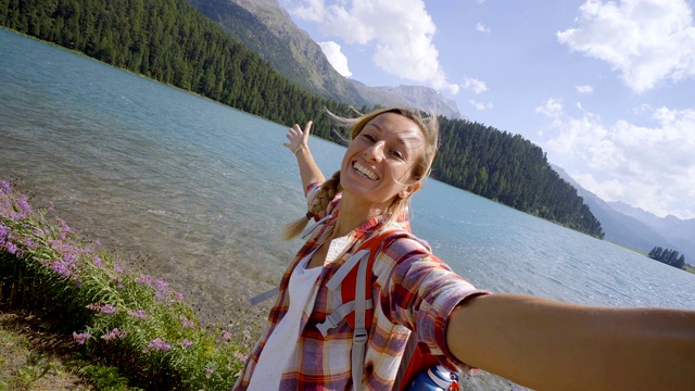 愉快的年轻女子在一个美丽的山湖边自拍，享受一天的徒步旅行;人们旅行户外活动的概念视频素材