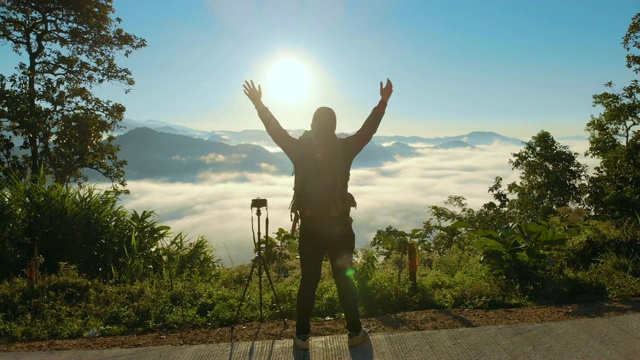 空中男性摄影师站在山上，举起他的手在早晨的日出视频素材