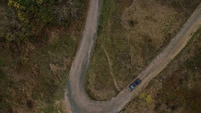 汽车在狭窄的道路上行驶的鸟瞰图。鸟瞰图的老黑色宝马在乡村道路上紧转弯视频下载