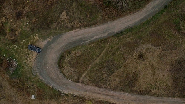 汽车在狭窄的道路上行驶的鸟瞰图。鸟瞰图的老黑色宝马在乡村道路上紧转弯视频素材