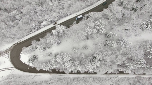 鸟瞰图转向公路在山区冬季积雪覆盖森林视频素材