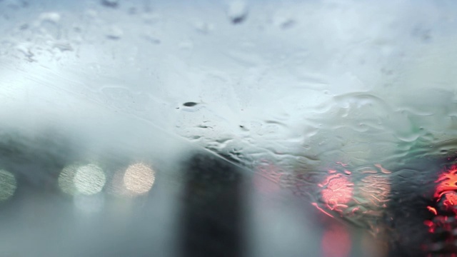 雨刷在潮湿天气下工作。透过车窗与雨滴的道路视图。视频素材
