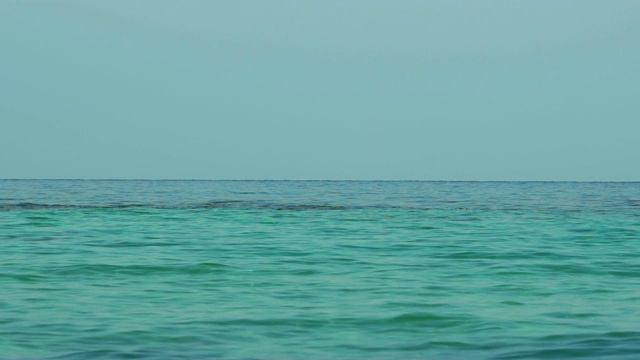 海或海洋中翠绿的水的慢动作。涟漪在清晨灰色的天空中荡漾。蓝色的天的概念。美丽的蔚蓝海岸。暑假在热带天堂海滩。视频素材