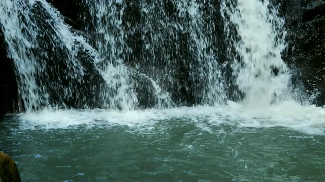 泰国野生丛林森林环境中美丽的瀑布自然风景慢镜头。旅行和冒险的观点，人们走向瀑布视频素材