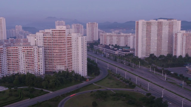 从夜晚到白天的惊人的时间流逝的住宅建筑和交通在光宝街的宽拍摄在晚上。朝鲜平壤视频素材