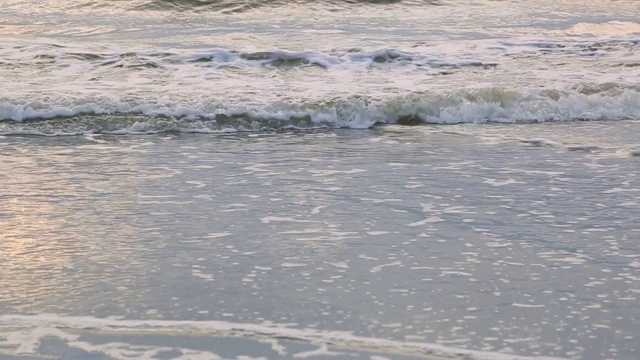 海浪靠近海岸，阳光在水中照耀。风景如画的白沙海岸冲刷着海浪。背景或纹理视频素材