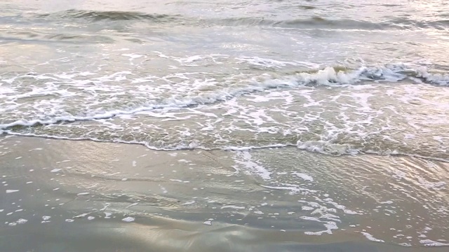 海浪靠近海岸，阳光在水中照耀。风景如画的白沙海岸冲刷着海浪。背景或纹理视频素材