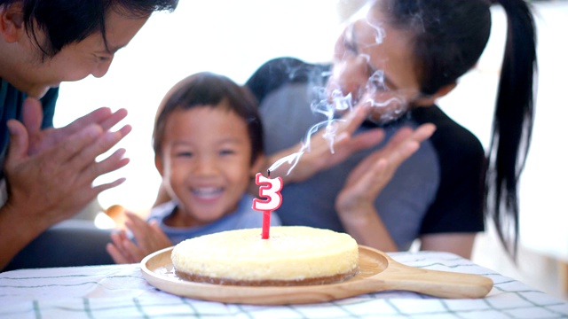 男孩和父母一起吹生日蜡烛。视频素材