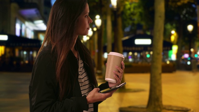 时髦女孩晚上在香榭丽舍大街用手机发短信视频素材