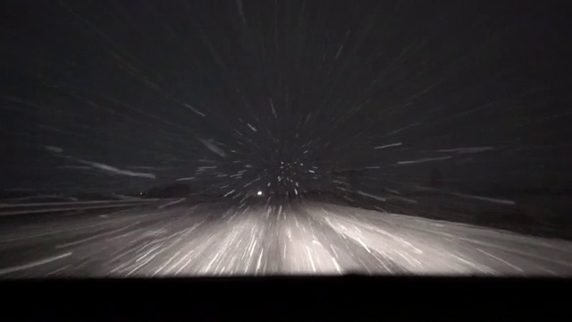 在有雪和暴雪的夜间道路上移动的汽车前灯视频下载