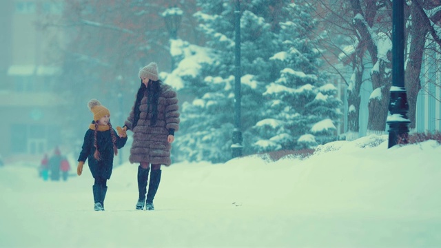 妈妈和女儿走在雪地里。他们在聊天，很开心。视频素材