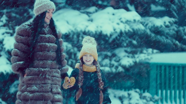 一位妇女带着孩子在雪地里走。他们是快乐的。冬天在雪下行走。视频素材