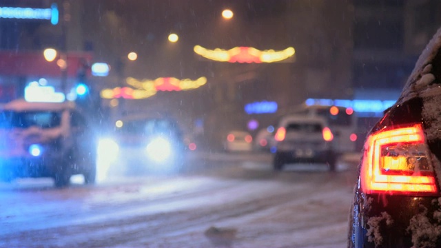 寒冷的冬夜，路上的汽车下着雪视频素材