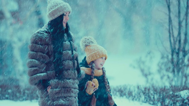 妈妈和女儿在大雪中散步聊天。冬天的天气。大雪。视频素材