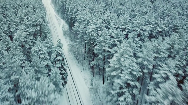 无人机在云杉林中白雪覆盖的乡村道路上高速追逐汽车，电影画面视频素材