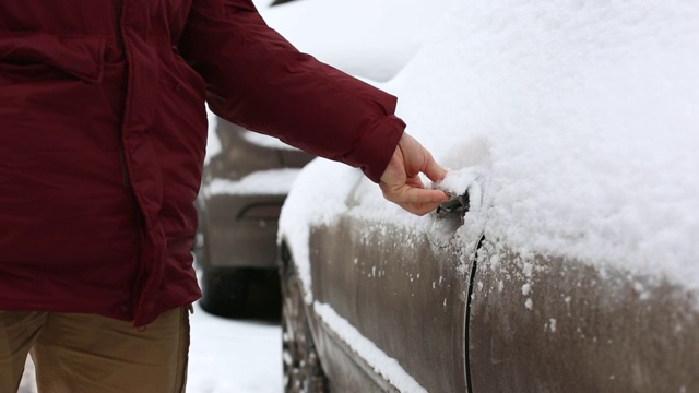 一名男子在住宅区用手清理汽车上的积雪视频素材