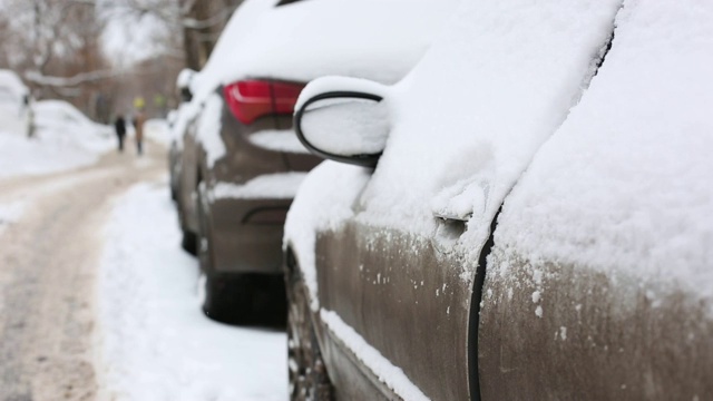 一名男子在住宅区用手清理汽车上的积雪视频素材