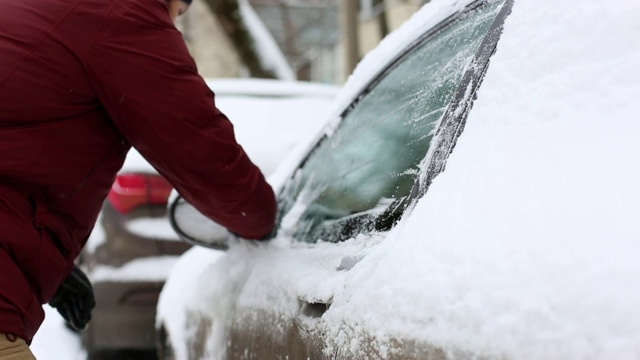 一名男子在住宅区用手清理汽车上的积雪视频素材