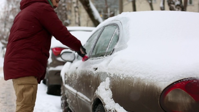 一名男子在居住区用刷子清理汽车上的积雪视频素材