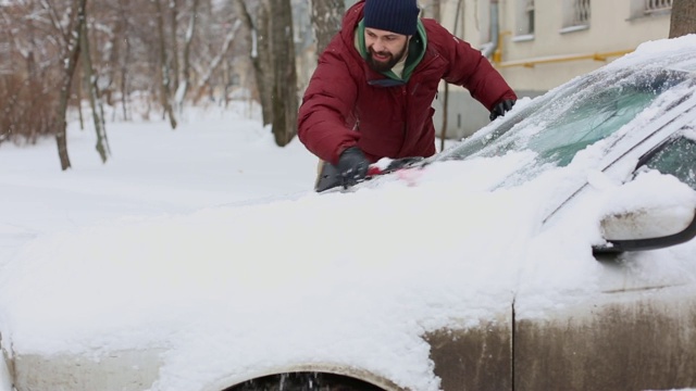 一名男子在居住区用刷子清理汽车上的积雪视频素材