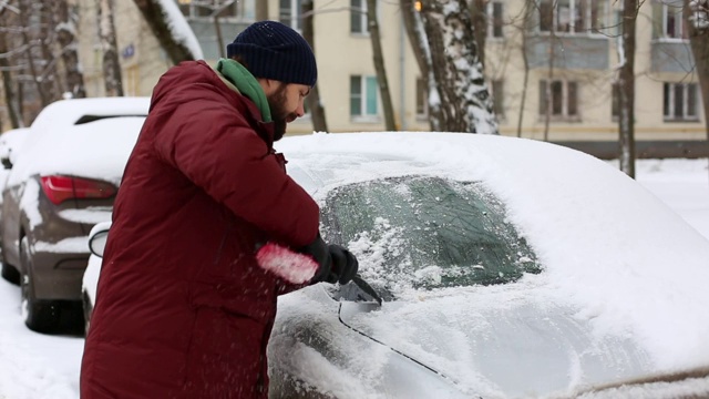 一名男子在居住区用刷子清理汽车上的积雪视频素材