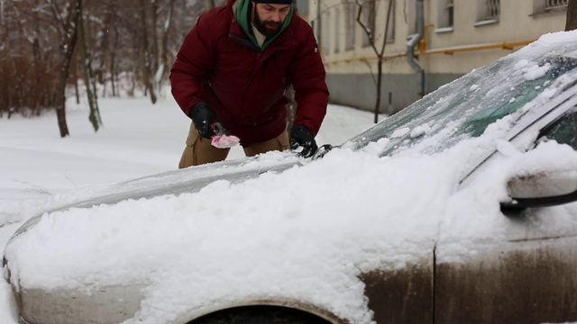 一名男子在居住区用刷子清理汽车上的积雪视频素材