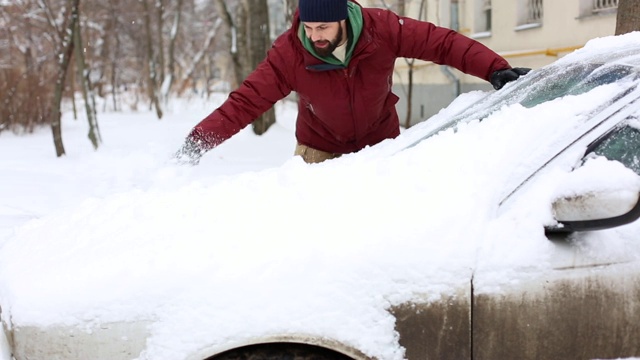 一名男子在居住区用刷子清理汽车上的积雪视频素材