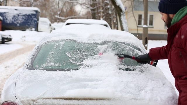 一名男子在居住区用刷子清理汽车上的积雪视频素材