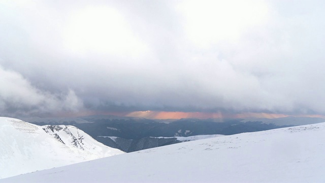 夕阳穿过暴风雪在冬季的山峦中时光流逝视频素材