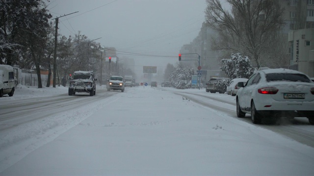 暴风雪来了。在被雪覆盖的道路上行驶的汽车。视频素材