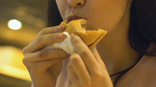 年轻饥饿的女人胃口吃美味的汉堡在快餐店视频素材