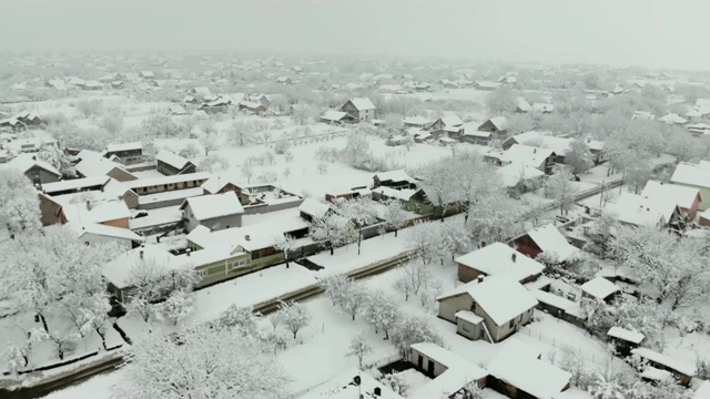 用无人机4K航拍被雪覆盖的村庄。白色多云的冬季天气视频下载