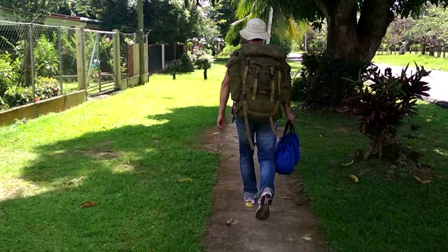 背包旅行者走在美丽的绿色道路上拍摄的业余手机相机镜头视频素材